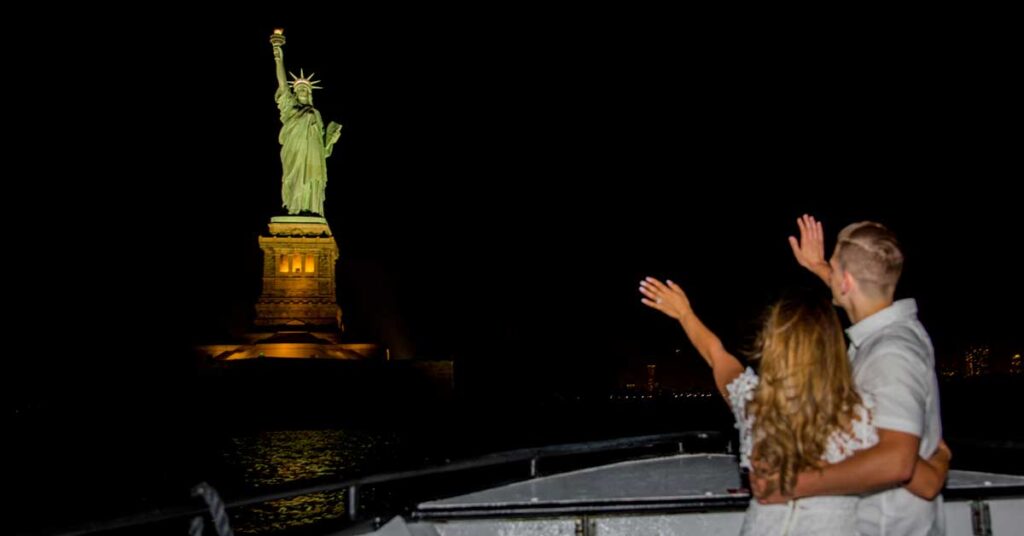 Couple waving at Statue of Liberty