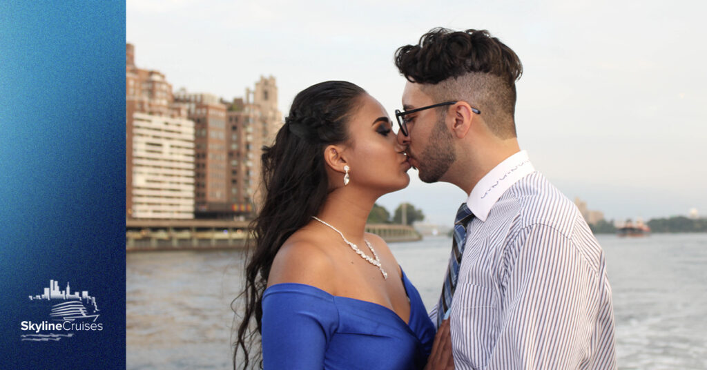 Couple kissing in front of the river and city skyline.